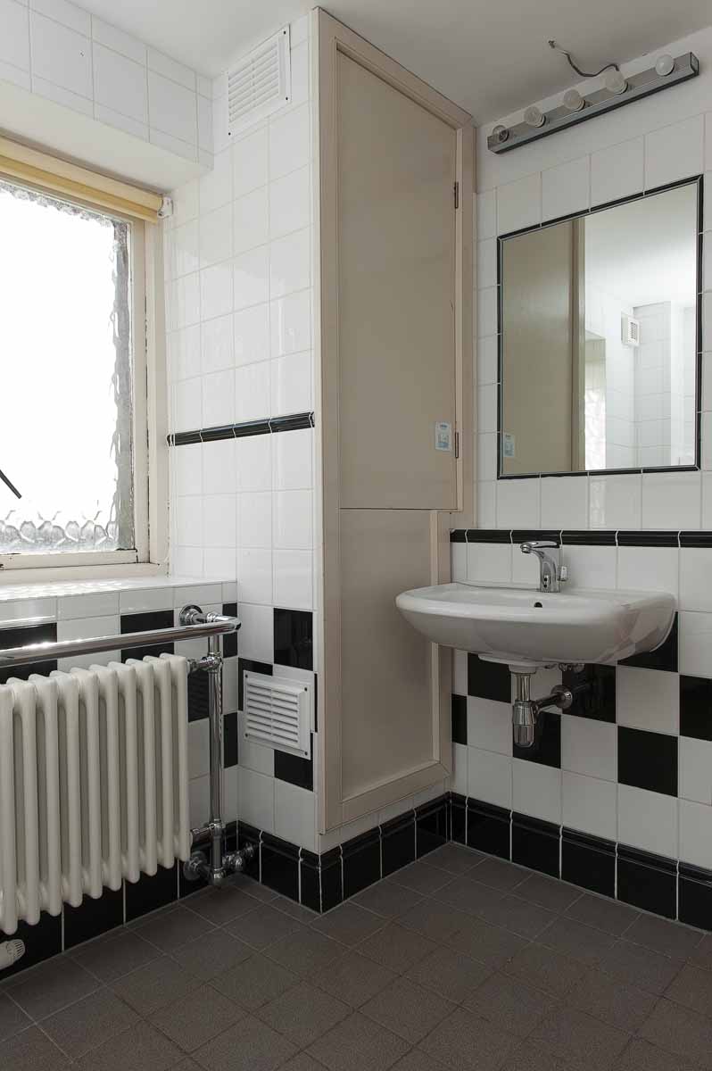 On-suite. Bathroom. Checked black and white tiles on the wall. Large mirror, sink.